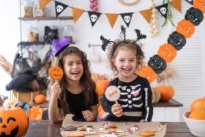 Two kids in costumes at home eating sweet treats on Halloween, needing dental care tips