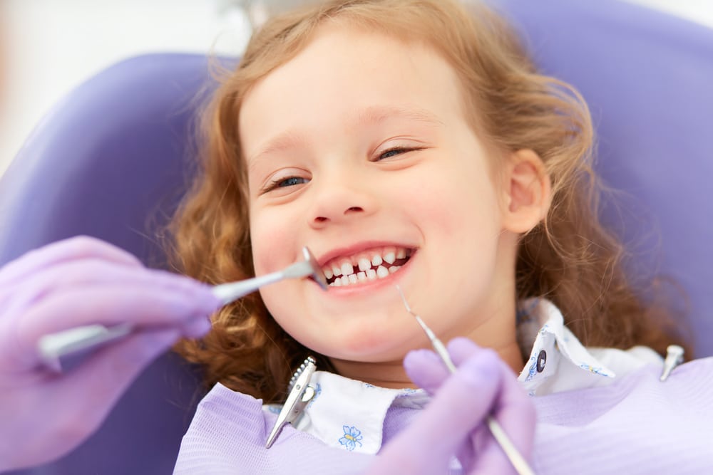 A child smiling while being examined at the dentist’s office