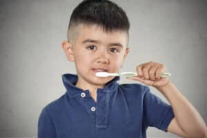 Young child brushing teeth to prevent cavities in Southern California